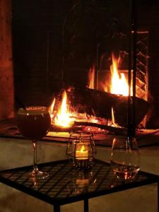 a fireplace with two glasses and two candles on a table at Domaine l'instant du Colibri in Le Mesnil-Théribus