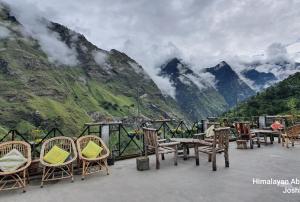 un grupo de sillas y mesas con montañas en el fondo en Abode Luxurious stay en Joshīmath