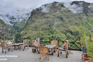 un patio con mesas y sillas frente a una montaña en Abode Luxurious stay en Joshīmath