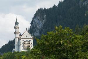 a castle on top of a mountain with trees at Hotel Pension Schwansee in Schwangau