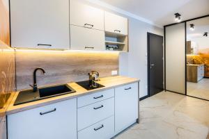 a kitchen with white cabinets and a sink at Przystanek Babia Apartamenty in Lipnica Wielka