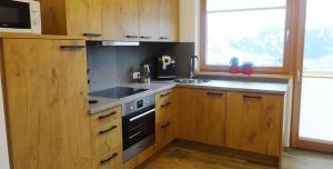 eine Küche mit Holzschränken, einem Herd und einem Fenster in der Unterkunft Ferienwohnung Natural B in Gerlosberg