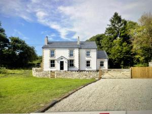 a white house with a fence in front of it at The House on the Common in Coity