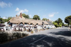 a building with tables and umbrellas on the side of a road at Castle Inn in West Lulworth