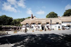 a building with a thatched roof with people sitting outside at Castle Inn in West Lulworth