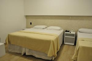 a bedroom with a large bed and a night stand at Hotel Peregrinos in Aparecida