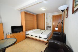 a bedroom with a bed and a desk and a tv at Miramar Playa II- Fincas Arena in Benidorm