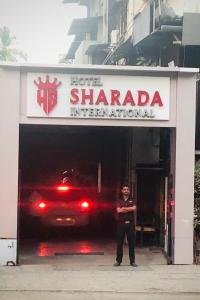 un hombre parado en la entrada de un garaje en HOTEL SHARADA INTERNATIONAL, en Thane