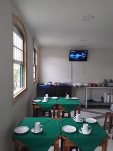 a room with four green tables and a tv at Casarão do DU in Campinas