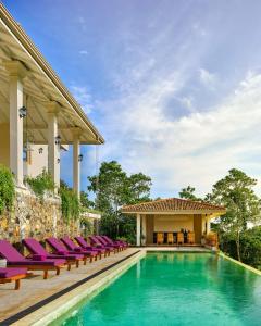 una piscina con tumbonas junto a una casa en The Divine Villa, en Talpe