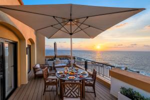 a dining table on a balcony with a view of the ocean at Corinthia St George's Bay in St. Julianʼs