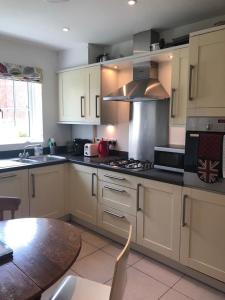 a kitchen with white cabinets and a table and a stove at Chichester Holiday Lets in Chichester