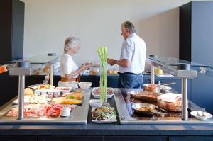 mężczyzna i kobieta stojący w kuchni przygotowując jedzenie w obiekcie Hotel Karmel w mieście Herentals