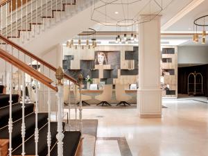 a lobby with a staircase with a table and chairs at Palacio de los Duques Gran Meliá - The Leading Hotels of the World in Madrid