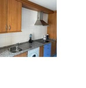 a kitchen with wooden cabinets and a sink at 8 de abril in Los Corrales de Buelna