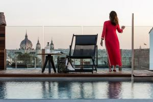 una mujer en un vestido rojo de pie en un balcón con una silla en Palacio de los Duques Gran Meliá - The Leading Hotels of the World, en Madrid