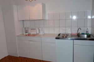 una cucina con armadi bianchi e lavandino di Ferienwohnung Tor zur Ostsee - a55964 a Mellenthin
