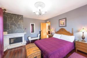 a bedroom with a purple bed and a fireplace at Agro da Gandarela in Teo