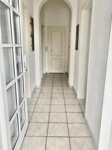 um corredor com uma porta branca e piso em azulejo em 19 Im Herrenfeld em Burgen
