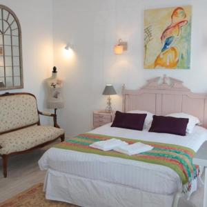 sypialnia z dużym łóżkiem i krzesłem w obiekcie Logis Hôtel & Restaurant Au Clos Paillé Charme & Caractère w mieście La Roche-Posay