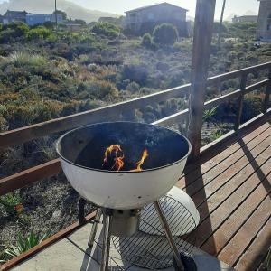 a grill on a deck with a view of a field at Brandys beach house bettys bay in Bettyʼs Bay