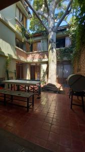 a picnic table and a tree in front of a building at OlasHostel in Mendoza