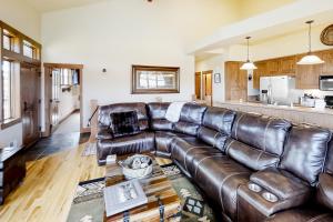 a living room with a leather couch and a kitchen at Mountain Sky in Granby