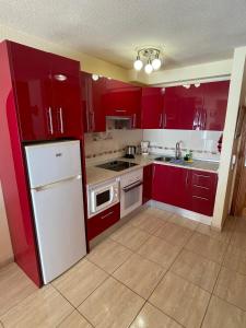 サンミゲル・デ・アボナにあるFairways Clubのキッチン(赤いキャビネット、白い冷蔵庫付)