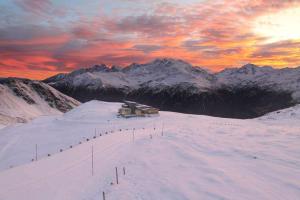 a ski lodge on a snow covered mountain with a sunset at Wallackhaus RegioJet Hotels in Heiligenblut +29 photos