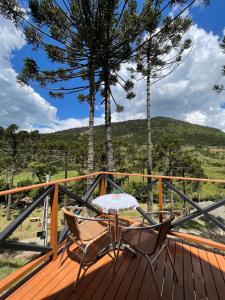 a wooden deck with a table and chairs on it at URUBICI - Cabana da Montanha in Mundo Novo