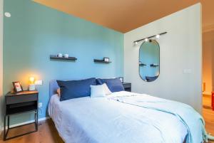 Dormitorio azul con cama y espejo en Top Living Apartments - Torino Centro en Turín