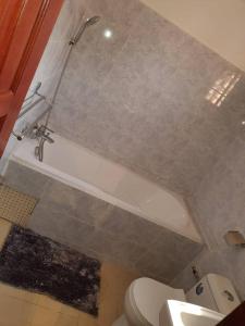 a bathroom with a tub and a toilet and a sink at Appartement chic au quartier Omnisport in Yaoundé