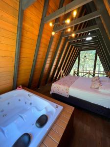 a bathroom with a tub in a room with a bed at URUBICI - Cabana da Montanha in Mundo Novo