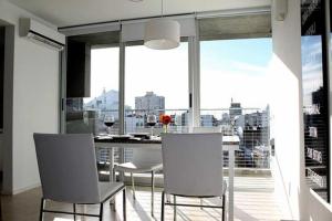 a dining room with white chairs and a large window at Altos de Maipu in Rosario
