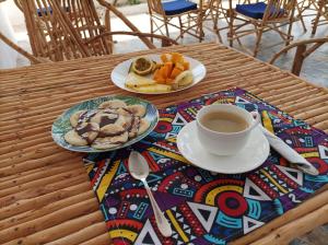 a table with two plates of food and a cup of coffee at Zanzicrown in Nungwi