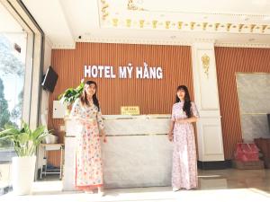 dos chicas de pie en frente de un hotel mi señal de colgar en Khách Sạn Mỹ Hằng, en Soc Trang