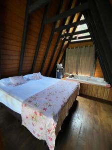 a bedroom with a bed and a tub in a attic at URUBICI - Cabana da Montanha in Mundo Novo