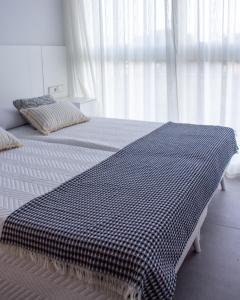 een bed met een zwart-witte deken erop bij Apartamento Ático Estrasburgo suites in Jávea
