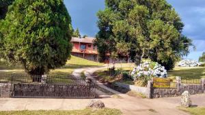 a house on a hill with a gate and trees at PARADOURO BOCA DA SERRA in São Francisco de Paula