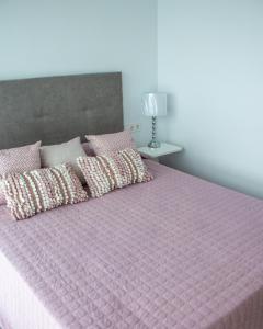 een bed met een roze dekbed en kussens erop bij Apartamento Ático Estrasburgo suites in Jávea