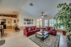 Villa Florida Vacation في كيب كورال: غرفة معيشة مع كنب احمر وطاولة