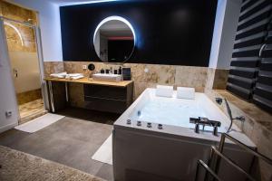 La salle de bains est pourvue d'une baignoire, d'un lavabo et d'un miroir. dans l'établissement BD ROOM LOVE ROOM COSY à SAINT-ETIENNE, à Saint-Étienne