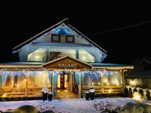 un edificio con luces de Navidad en la nieve en Pensiunea Galileo, en Borşa