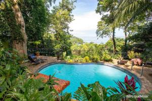 a swimming pool in the middle of a garden at Mango Moon Villa in Manuel Antonio