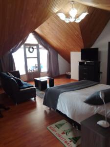 a bedroom with a bed and a chair and a clock at Lago de Tota Las Heliconias in Aquitania