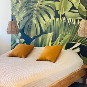 un letto con 2 cuscini e un murale di foglie di Studio tropical, beautifully renovated, sea view ad Anse Marcel