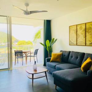 ein Wohnzimmer mit einem blauen Sofa und einem Tisch in der Unterkunft Studio tropical, beautifully renovated, sea view in Anse Marcel 