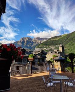 a patio with tables and chairs with mountains in the background at Hotel Villa de Torla in Torla-Ordesa