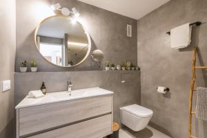 een badkamer met een wastafel en een spiegel en een toilet bij Cofisa Coral in Jávea +21 foto's
