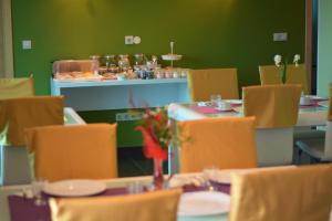 a dining room with tables and chairs and a green wall at Eluize Inn Dubrovnik in Dubrovnik